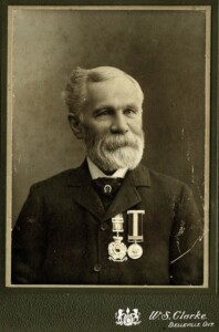 Photographic portrait of a bearded older man wearing two medals.